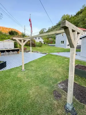 a patio with two wooden pergolas in a yard at Charming Seaside Cabin With Amazing View in Hardbakke