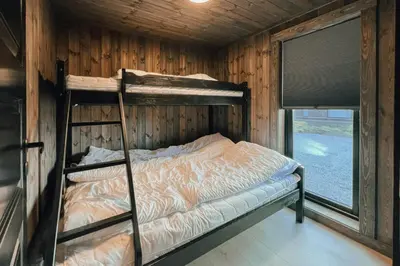a bunk bed in a wooden room with a window at Charming Summer Farm Hut At Sjusjøen in Torpo