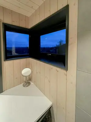 a small kitchen with a stool and two windows at Stylish Mountain Cabin In Hallingdalen in Flå