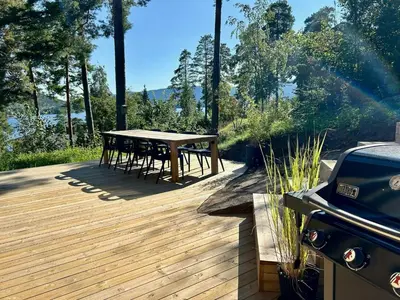a wooden deck with a table and a grill at New Cabin By Tyrifjorden For Relaxing Holidays in Gjesval
