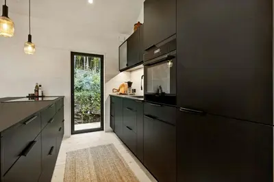 a kitchen with black cabinets and a sink at New Cabin By Tyrifjorden For Relaxing Holidays in Gjesval