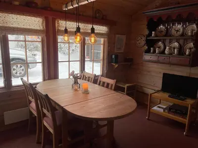 a dining room with a wooden table and a television at A Cozy, Rustic Retreat With Fireplace And Terrace in Beitostøl