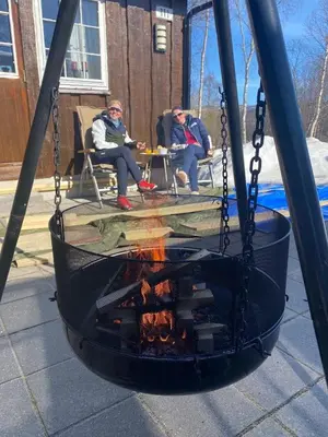 two people sitting around a fire in a swing set at Charming and cozy cabin in Geilo in Geilo