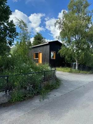 a small house with a fence next to a road at Mikrohus i byen - Tinyhouse Hamar city in Hamar