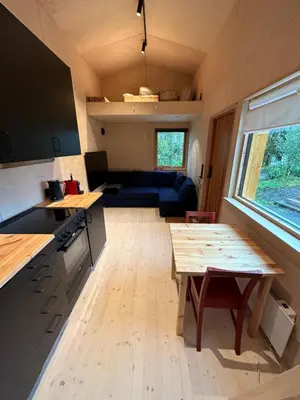 a kitchen and living room with a table and a couch at Mikrohus i byen - Tinyhouse Hamar city in Hamar