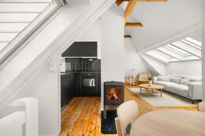an attic living room with a stove and a couch at Bryggen Historical Townhouse I Rooftop Views! in Bergen