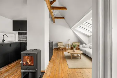 a living room with a stove and a kitchen at Bryggen Historical Townhouse I Rooftop Views! in Bergen