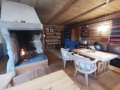 a living room with a fireplace and a table and chairs at Brattland Sæter in Strond