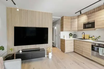 a kitchen with a large flat screen tv on a wall at Lys og koselig leilighet leies ut til Ski VM 2025 in Trondheim