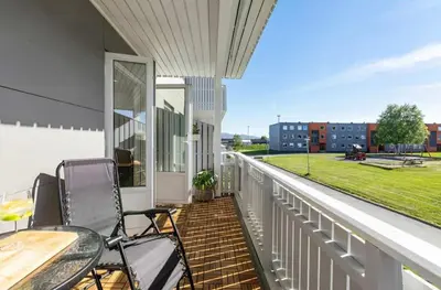 a balcony with two chairs and a table and a field at Lys og koselig leilighet leies ut til Ski VM 2025 in Trondheim