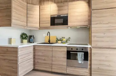 a kitchen with wooden cabinets and a stove top oven at Lys og koselig leilighet leies ut til Ski VM 2025 in Trondheim