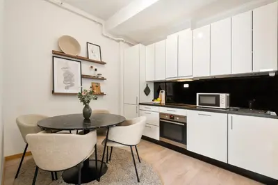a kitchen with white cabinets and a table and chairs at 3-roms leilighet i hjertet av Sandviken in Bergen