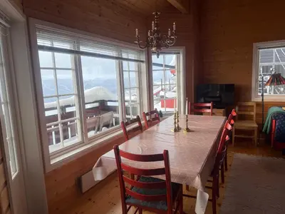 a dining room with a table and chairs and windows at Ski-In Ski-Out Cozy Retreat With Mountain Views in Beitostøl