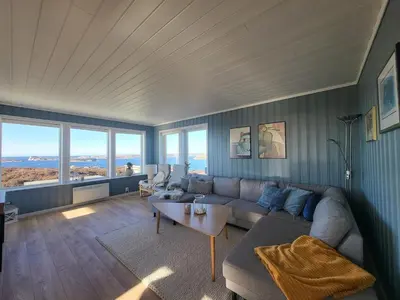 a living room with a couch and a table at Stor hytte med fantastisk utsikt in Vikso