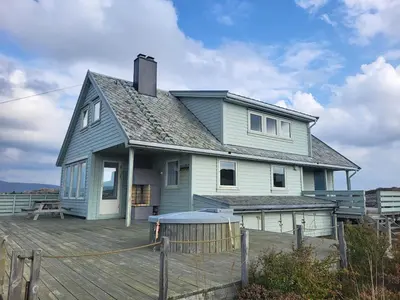 a house on a wooden deck with a fence at Stor hytte med fantastisk utsikt in Vikso