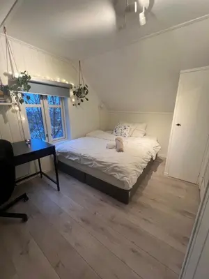 a bedroom with a bed and a desk and a window at Cozy apartment on the hill in Trondheim