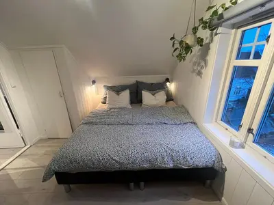a bed in a room with two windows at Cozy apartment on the hill in Trondheim
