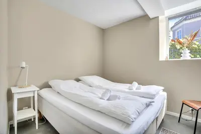 a white room with white sheets on a bed at Bryggen Nest in Bergen