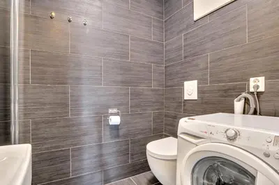 a bathroom with a toilet and a washing machine at Bryggen Nest in Bergen
