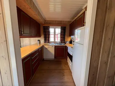 a kitchen with wooden cabinets and a white refrigerator at Nostalgic Cabin With 3 Br, Fireplace, And Terrace in Beitostøl