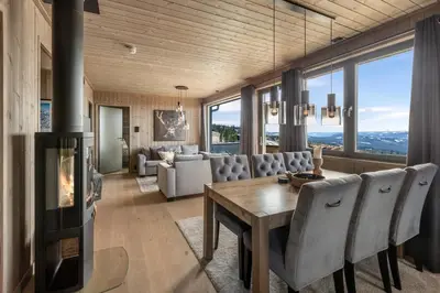 a living room with a fireplace and a table and chairs at New modern apartment with ski in out in Hafjell in Hafjell