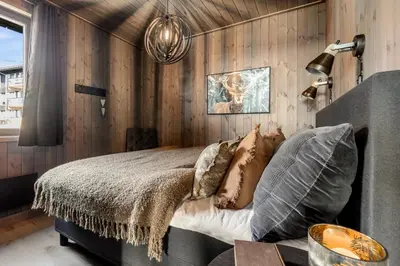 a bedroom with wooden walls and a bed with pillows at New modern apartment with ski in out in Hafjell in Hafjell