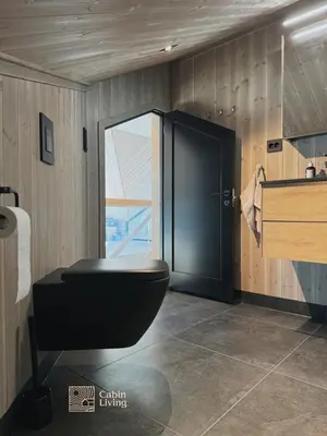a bathroom with a black toilet and a sink at New modern cabin at Norefjell with sauna in Noresund