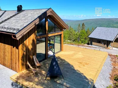 a house with a wooden deck with a view at New modern cabin at Norefjell with sauna in Noresund