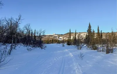 a snow covered field with tracks in the snow at Moderne Hytte Midt I Skibakken in Ryfoss