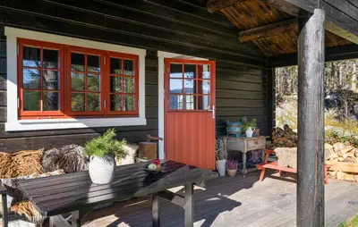 a porch of a wooden cabin with a bench and a red door at Amazing Home In Hovet With Sauna in Hovet