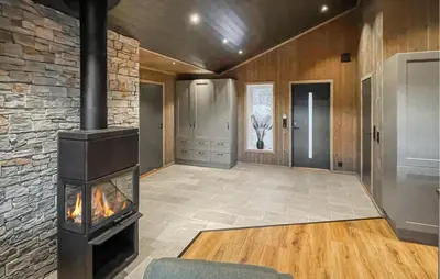 a living room with a fireplace and a stone wall at 4 Bedroom Gorgeous Home In Koppang in Koppang