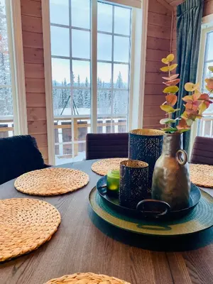 a table with plates and a vase with flowers on it at Beitobygda Getaway ,Nature And Luxury in Beitostøl