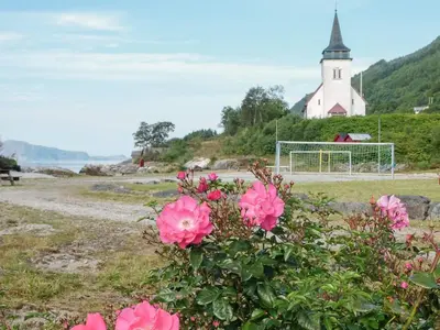 a field of flowers with a church in the background at 4 person holiday home in Sørbøvåg in Sørbø