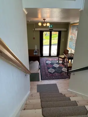 a hallway with stairs leading to a room with a door at Sognefjord Gjesteheim in Vangsnes