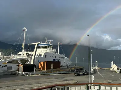 a large white boat with a rainbow in the background at Sognefjord Gjesteheim in Vangsnes