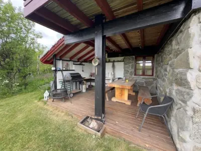 an outdoor deck with a grill and a table at Mountain Home With 5 Bedrooms And 2 Fireplaces in Beitostøl