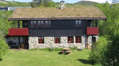 a house with a grass roof with a table in front of it at Mountain Home With 5 Bedrooms And 2 Fireplaces in Beitostøl