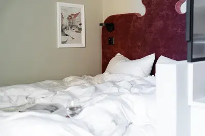 an unmade bed with a glass of wine on it at VANDER Altona in Bergen
