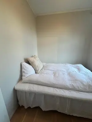 a bedroom with a bed with white sheets and pillows at Sentrumsnær trivelig leilighet in Bergen