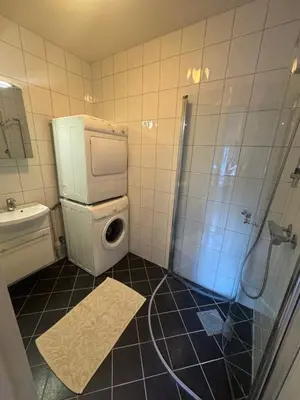 a bathroom with a shower and a washing machine at Sentrumsnær trivelig leilighet in Bergen
