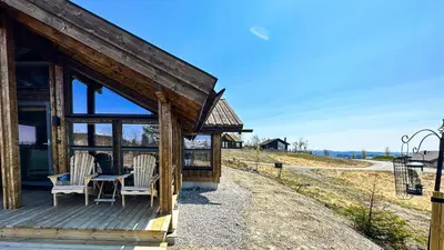 a cabin with a table and chairs on a porch at Cozy Cabin With Fantastic Mountain Views In Oppheimåsen in Torpo