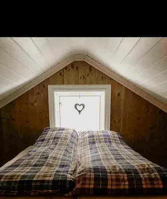a bed in a room with a heart in a window at Cozy Modern Cabin Near Sjusjøen in Mesnali
