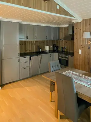 a kitchen with wooden cabinets and a wooden table at Cozy Modern Cabin Near Sjusjøen in Mesnali