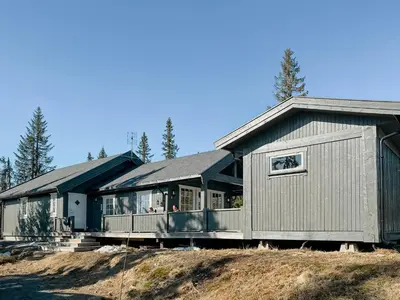 a large house on a hill with trees in the background at Cozy Modern Cabin Near Sjusjøen in Mesnali