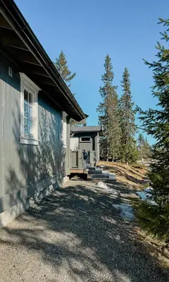 a house with a porch next to a yard at Cozy Modern Cabin Near Sjusjøen in Mesnali