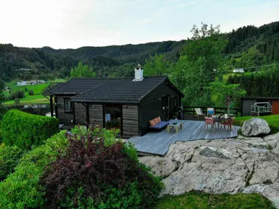 a small cabin with a deck on a mountain at Modern And Rustic Cabin With Fjord View In Samnanger in Årland