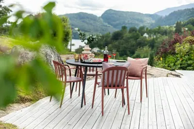 a table and chairs sitting on a wooden deck with a view at Modern And Rustic Cabin With Fjord View In Samnanger in Årland