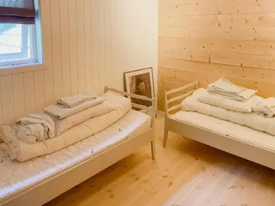 two beds in a room with a wooden wall at Cozy Modern Cabin In West Norway With View in Davik