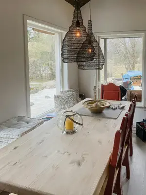 a dining room with a wooden table with chairs and windows at Cozy Modern Cabin In West Norway With View in Davik