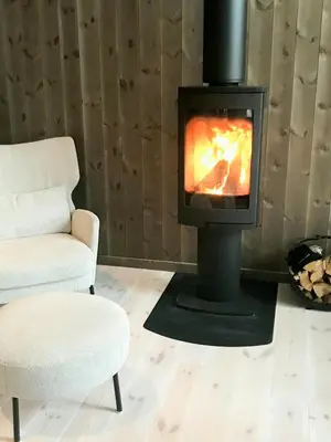 a fireplace in a living room with a chair and a chair at Large Cabin Near Hardangervidda With Sunny Veranda in Veggli